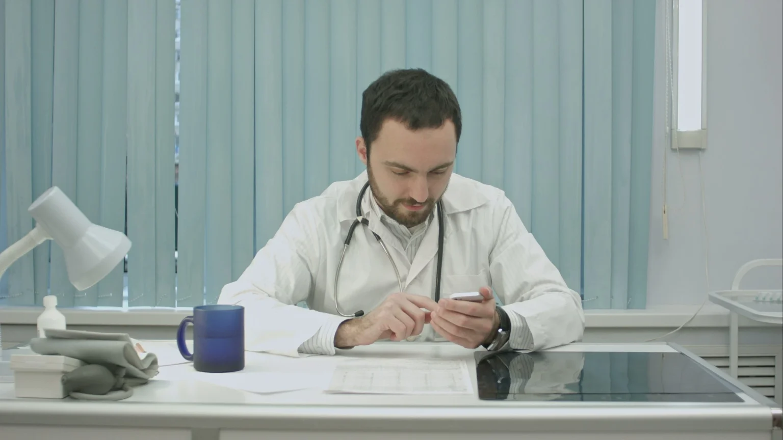 Profissional de saúde utilizando smartphone em consultório, representando o uso do App Porto Seguro Saúde